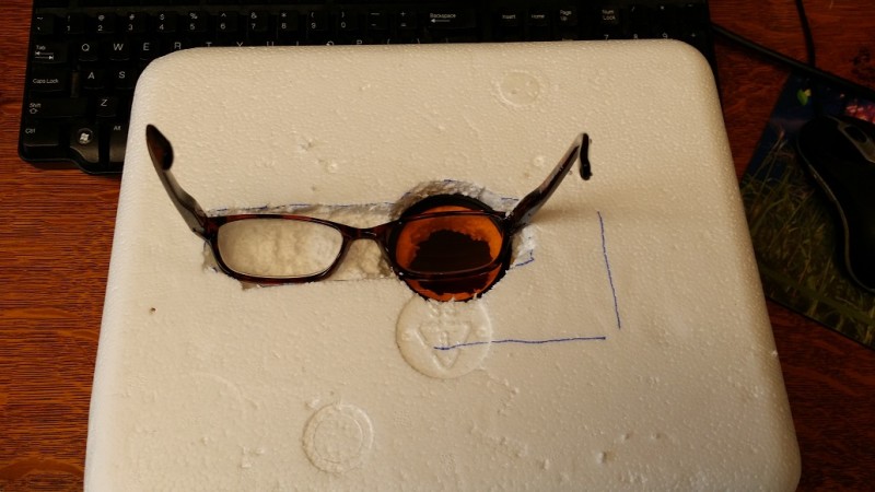 Cut out a hole in a Styrofoam box for one lens and make a recess to keep the other half of the glasses in place