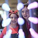 Two smiling girls observe a colourful LED arrangement