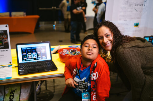 A boy participating in Coolest Projects shows off his tech project together with an adult.