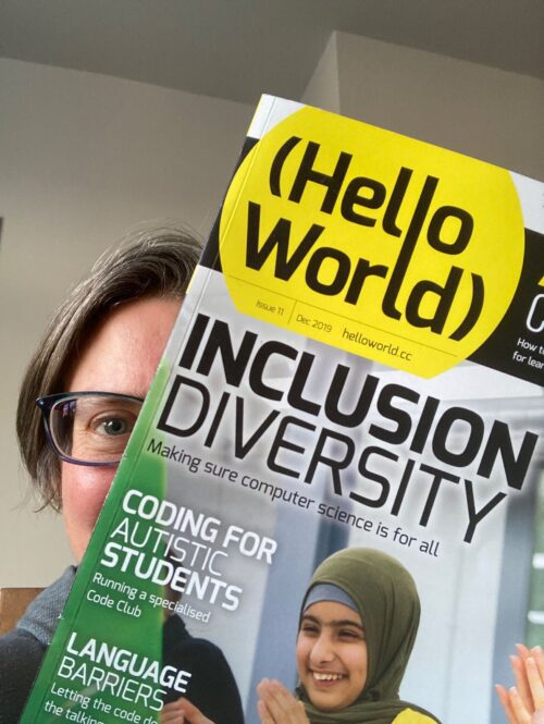 An educator holds up a copy of Hello World magazine in front of their face.